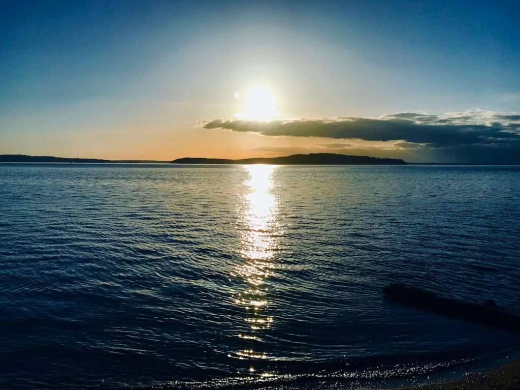 the sun is setting over the water of a lake
